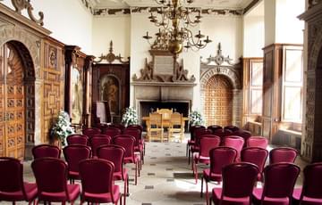 An ornate hall with chairs set out for a wedding ceremony