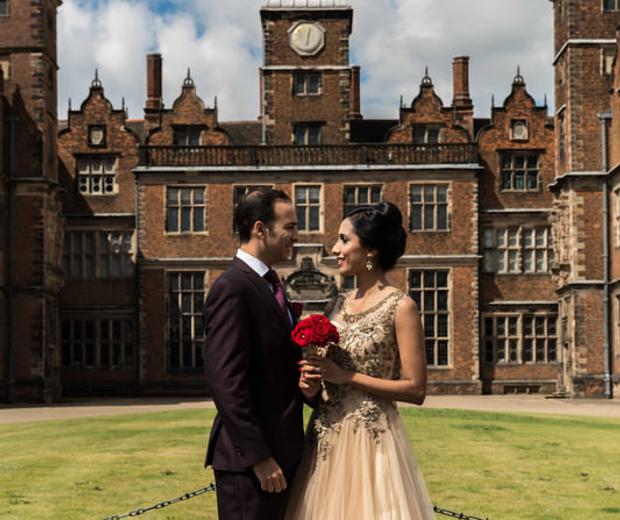 A bride and groom standing outside with Aston Hall in the background