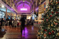 Festive indoor dining with Christmas tree, decorated high ceilings, and neon "Made in Birmingham" sign.