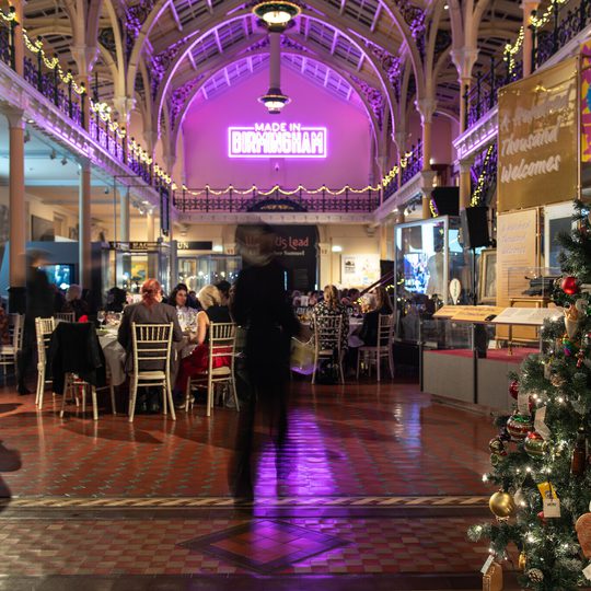 Festive indoor dining with Christmas tree, decorated high ceilings, and neon "Made in Birmingham" sign.