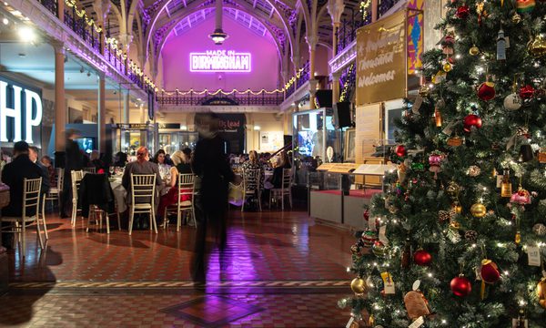 Festive indoor dining with Christmas tree, decorated high ceilings, and neon "Made in Birmingham" sign.