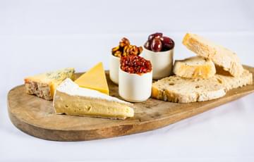 A cheese board with bread, cheeses and spreads.