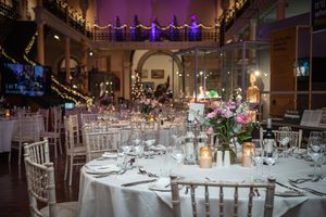 Elegant gallery set up with round tables decorated with, floral centrepieces, candlelights, and festive decorations.