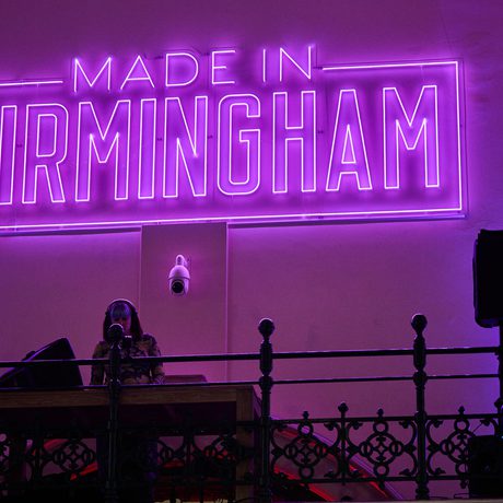 A large neon 'Made in Birmingham' sign with DJ playing underneath.
