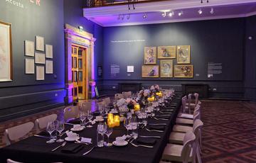 Along table laid out for dinner in the exhibition space.