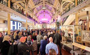 Lots of visitors in two level gallery which has an ironwork ceiling and balcony.