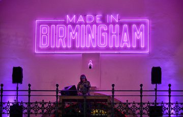Made in Birmingham in neon lights with a DJ playing underneath.