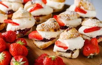 Close up of scones with jam, cream and strawberries.