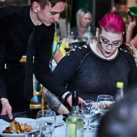 A waiter serving meals to a person at a table.