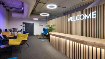 A modern reception area with reception desk, neon 'Welcome' sign and seating areas.