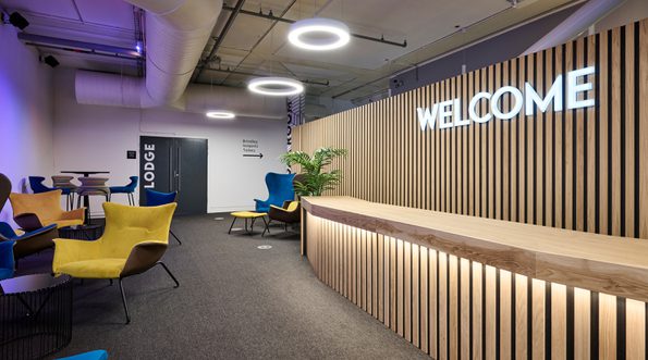 A modern reception area with reception desk, neon 'Welcome' sign and seating areas.