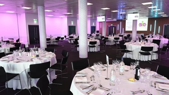 A room set up for a meal with lots of circular tables.