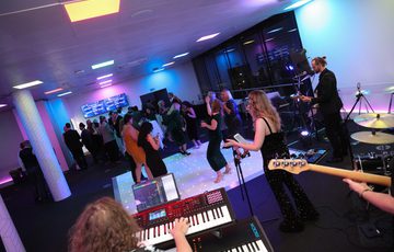 An angle shot of people dancing on a dance floor with a band playing.