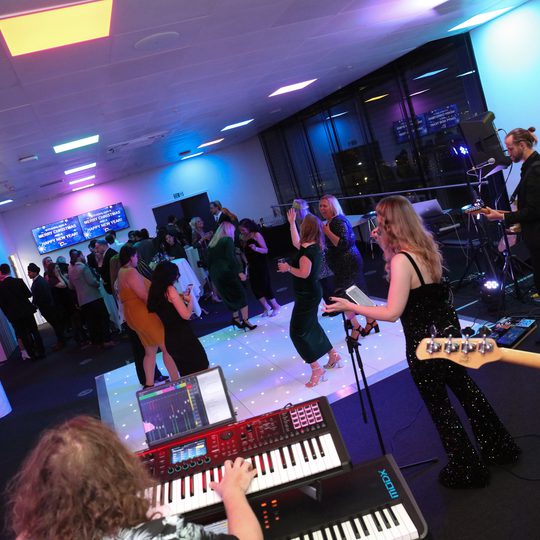 An angle shot of people dancing on a dance floor with a band playing.