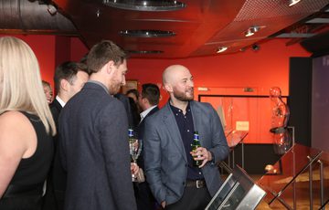 A group of people smiling looking at a gallery display.