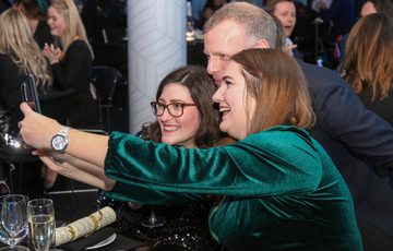 Three people smiling and posing for a selfie photograph.