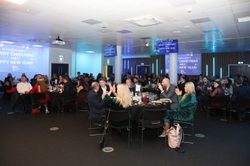 A wide shot of a dinner party in the events suite with lots of people seated at circular tables.