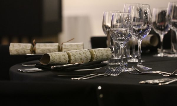 Close up of a table laid out with glasses, cutlery and crackers.